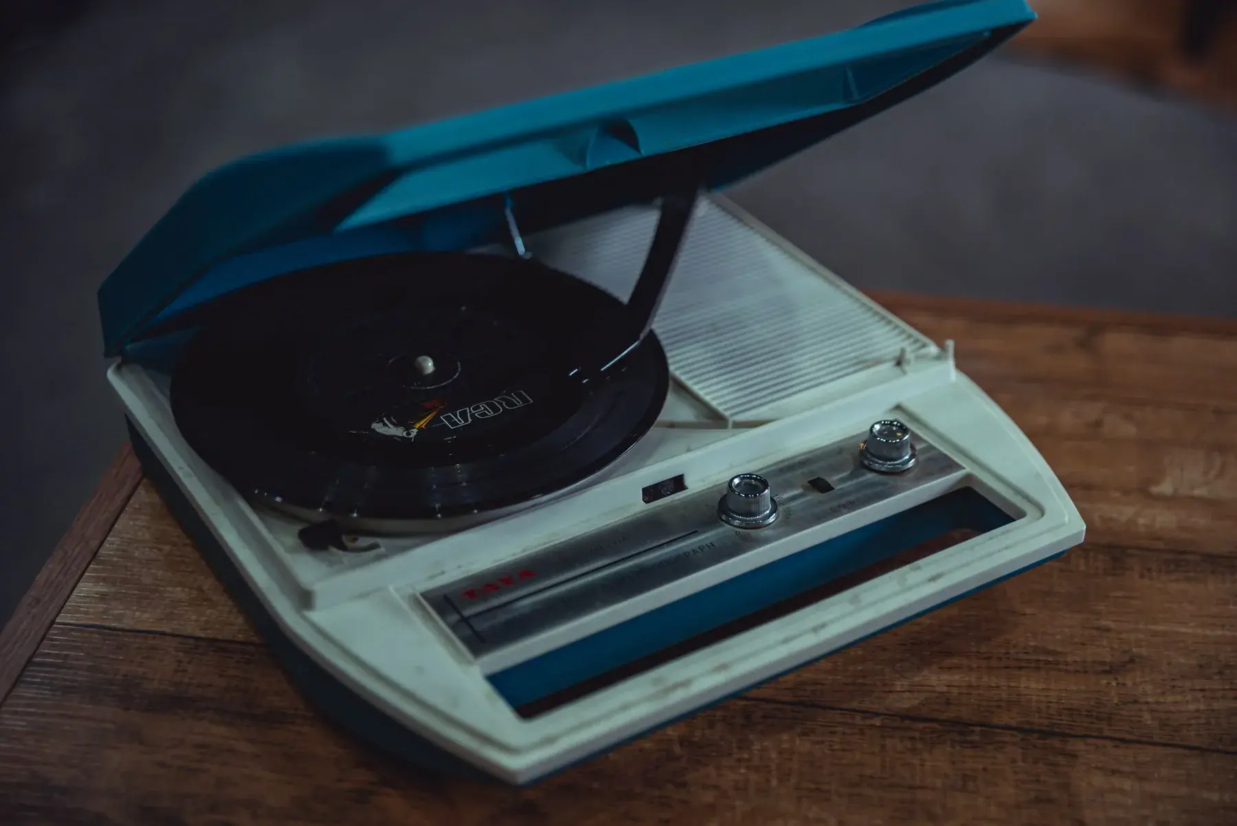 A retro teal record player on a wooden table.
