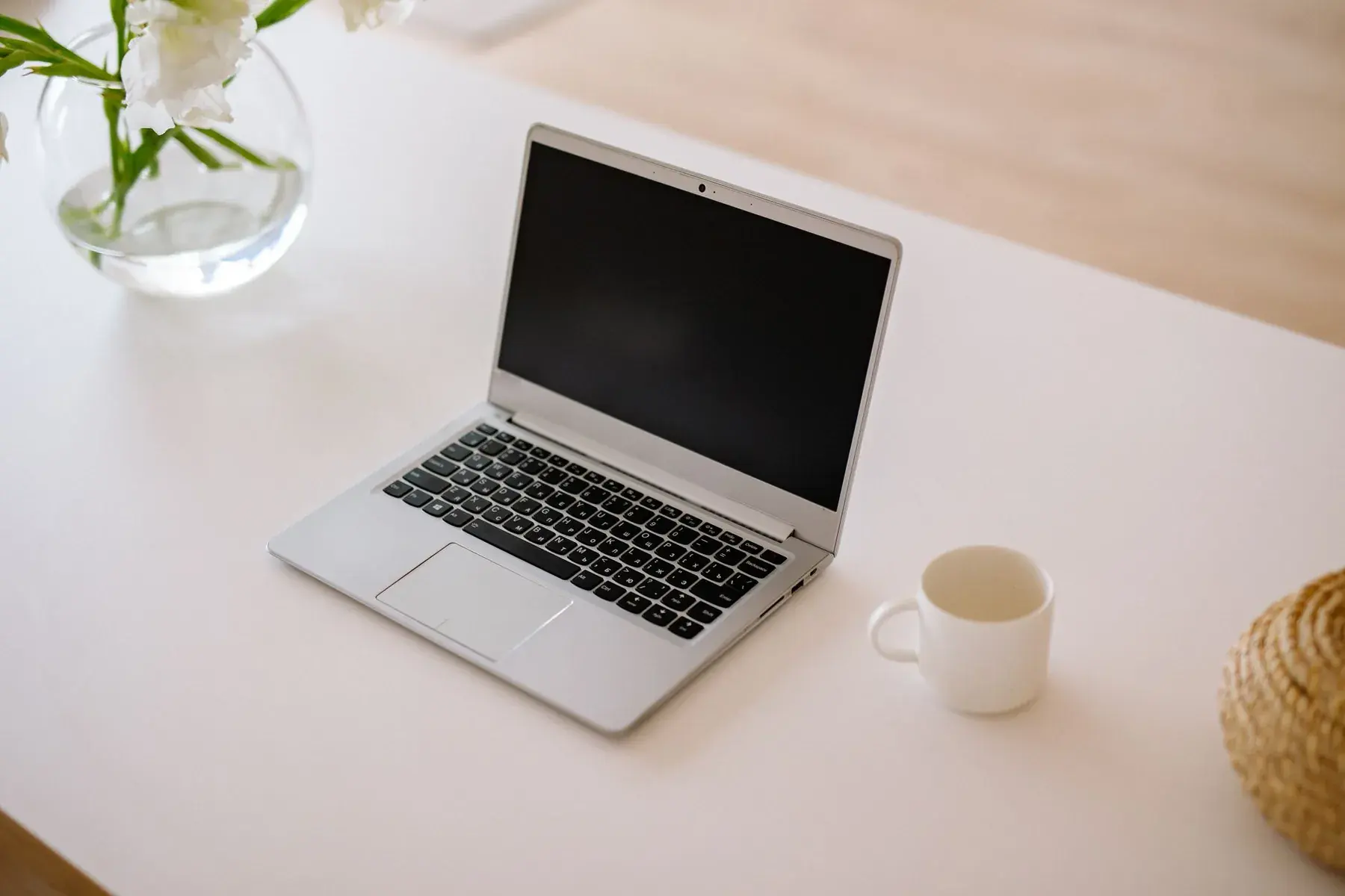 An open laptop on a white desk in daylight.