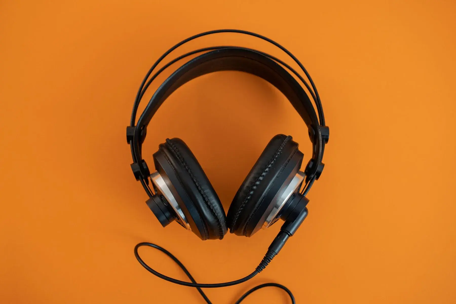 Black headphones on an orange background.