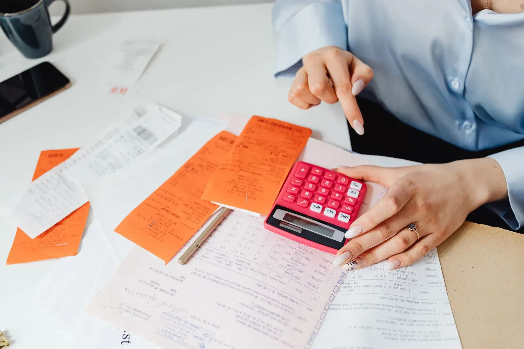 Invoices and receipts spread out, with a pink calculator.